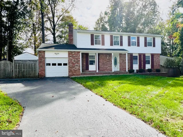 a view of a house with a yard and a large tree