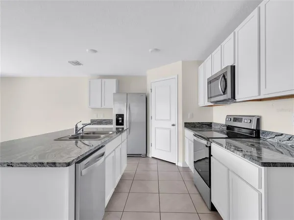 a kitchen with granite countertop a sink stove and cabinets