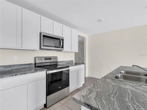 a kitchen with granite countertop a stove top oven microwave and cabinets