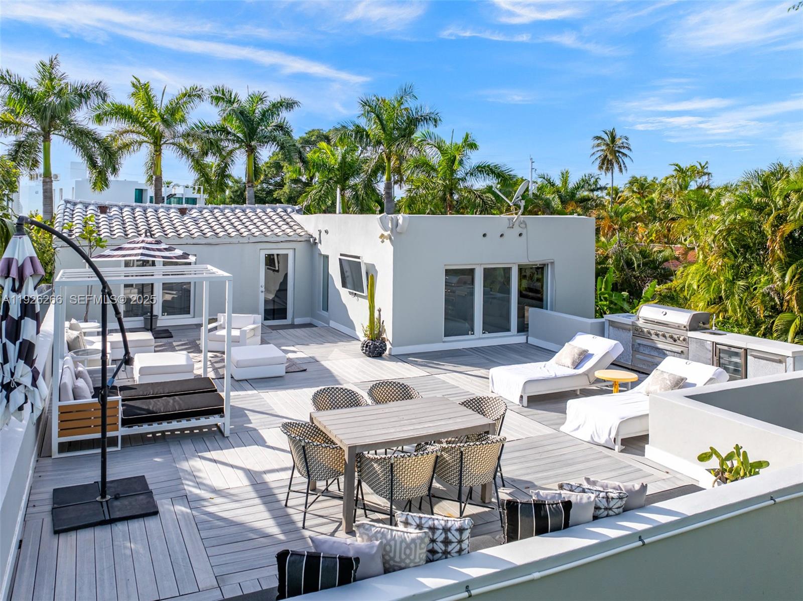 2729 North Bay Road Miami Beach, FL 33140 - Photo 3 of 41 a view of a patio with couches table and chairs with potted plants and wooden floor
