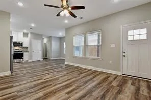 a view of an empty room with window and wooden floor