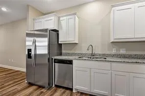 a kitchen with granite countertop a refrigerator sink and cabinets