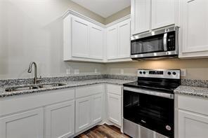 519 West Bond Street Denison, TX 75020 - Photo 7 of 14 a kitchen with granite countertop white cabinets and stainless steel appliances