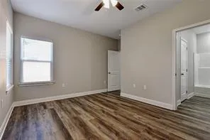 an empty room with wooden floor cabinet and windows