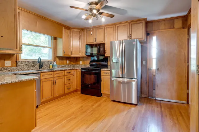 a kitchen with granite countertop stainless steel appliances a refrigerator cabinets and wooden floor