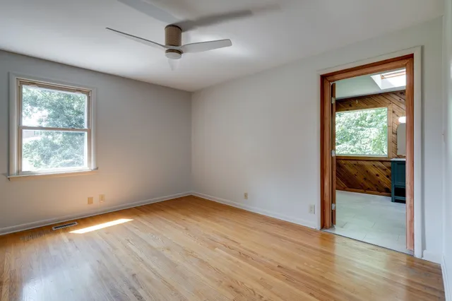 a view of empty room with wooden floor and fan