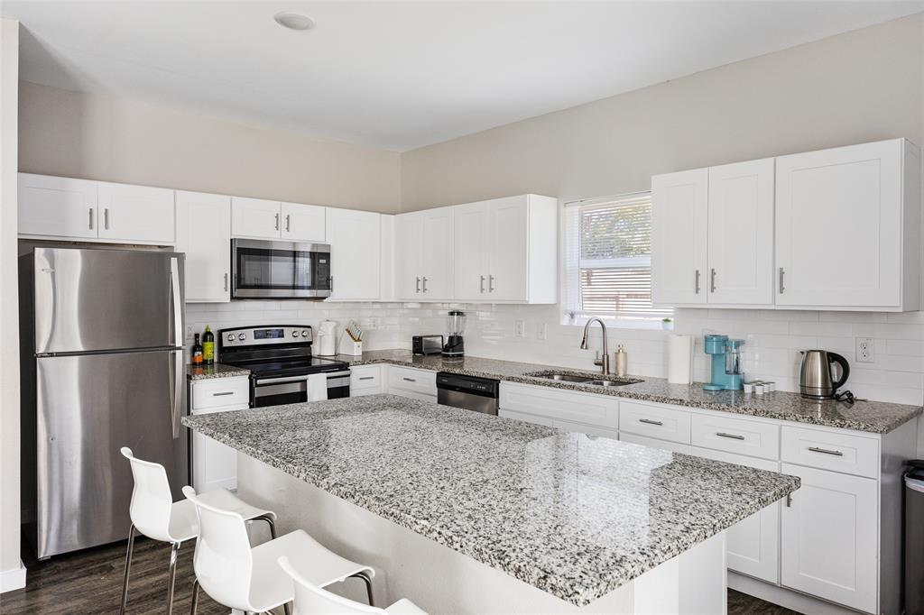 5006 Colonial Avenue Dallas, TX 75215 - Photo 7 of 25 a kitchen with stainless steel appliances granite countertop a sink stove refrigerator and white cabinets