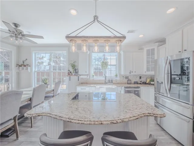 a kitchen with kitchen island a large counter top space appliances and a chandelier