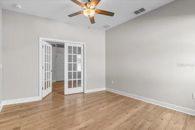 an empty room with wooden floor closet and windows