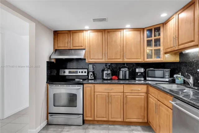 a kitchen with granite countertop white cabinets stainless steel appliances and sink