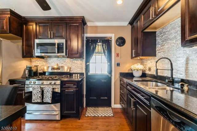 a kitchen with stainless steel appliances granite countertop a stove a sink and a microwave