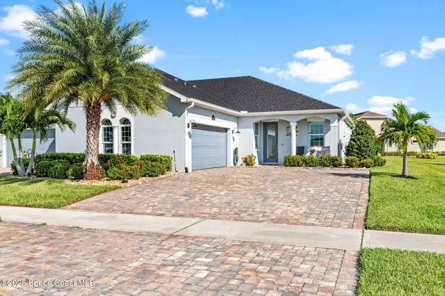 a view of a white house with a yard and palm trees
