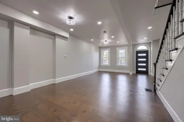 an empty room with stairs and wooden floor