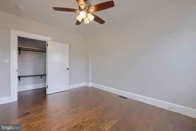 an empty room with wooden floor closet and windows