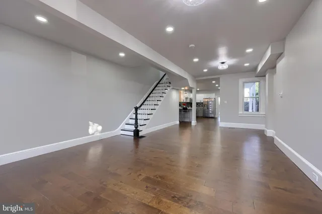 a view of an empty room with wooden floor and stairs