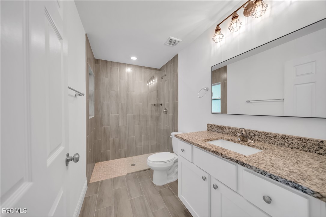 2156-2154 Edison Avenue Fort Myers, FL 33901 - Photo 21 of 38 a bathroom with a granite countertop sink a toilet a mirror and shower