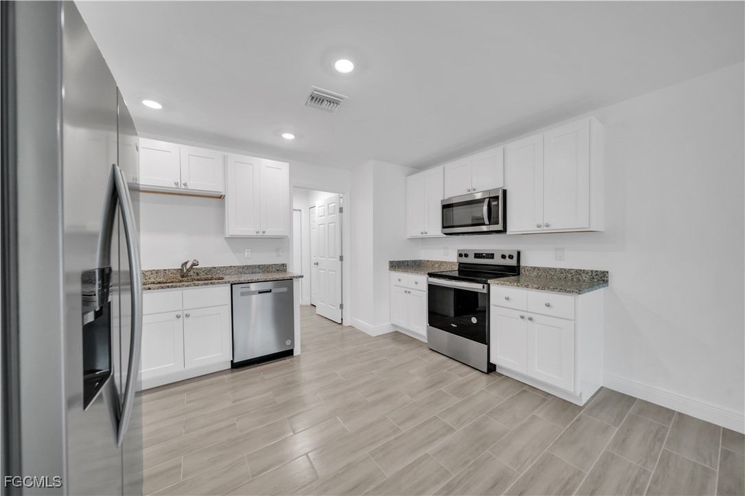2156-2154 Edison Avenue Fort Myers, FL 33901 - Photo 23 of 38 a kitchen with granite countertop white cabinets and stainless steel appliances