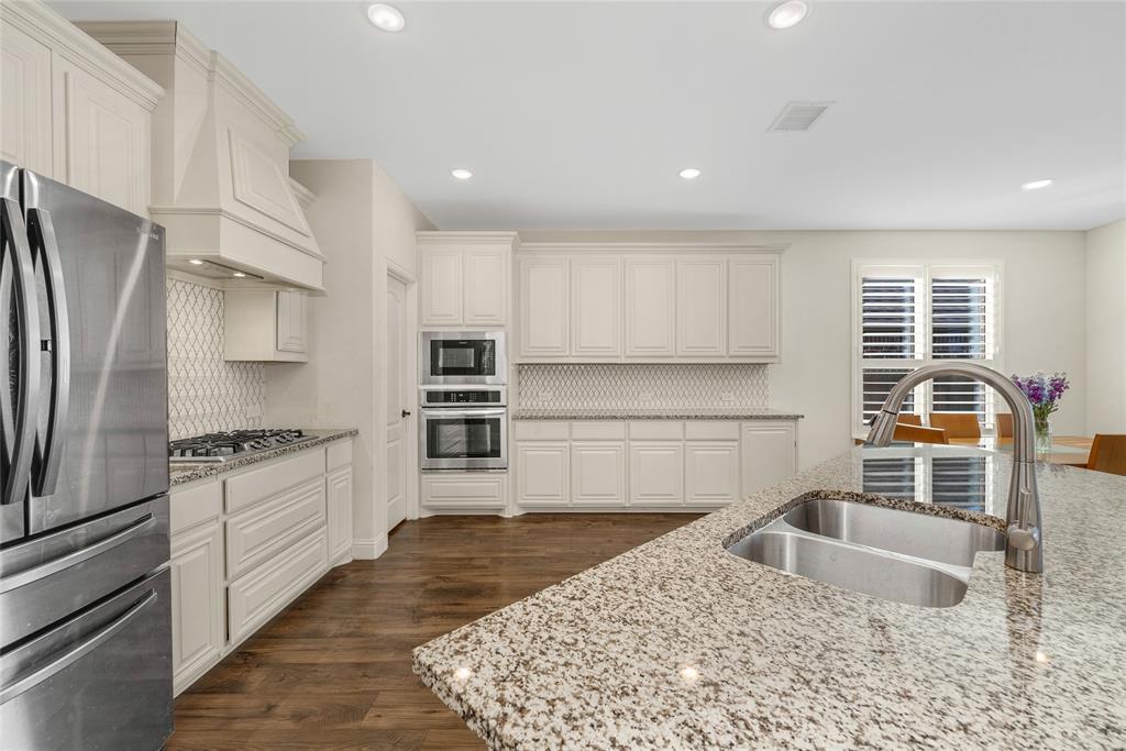 2203 Vista Ridge Road Melissa, TX 75454 - Photo 7 of 40 Kitchen featuring stainless steel appliances, light stone countertops, dark wood-style flooring, white cabinetry, and tasteful backsplash