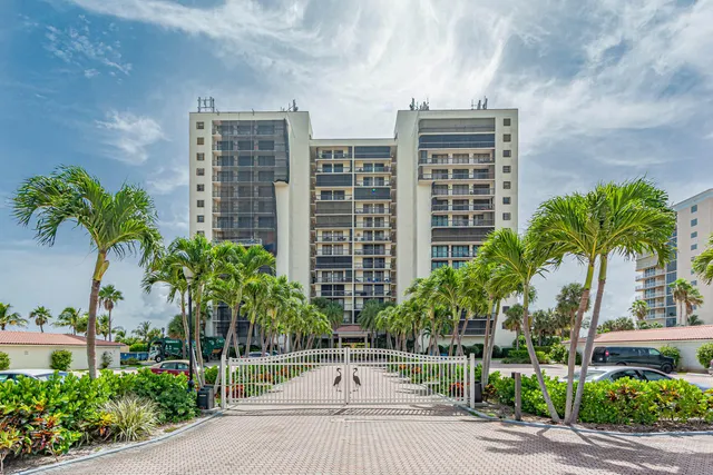 a front view of multi story residential apartment building with yard and sign board