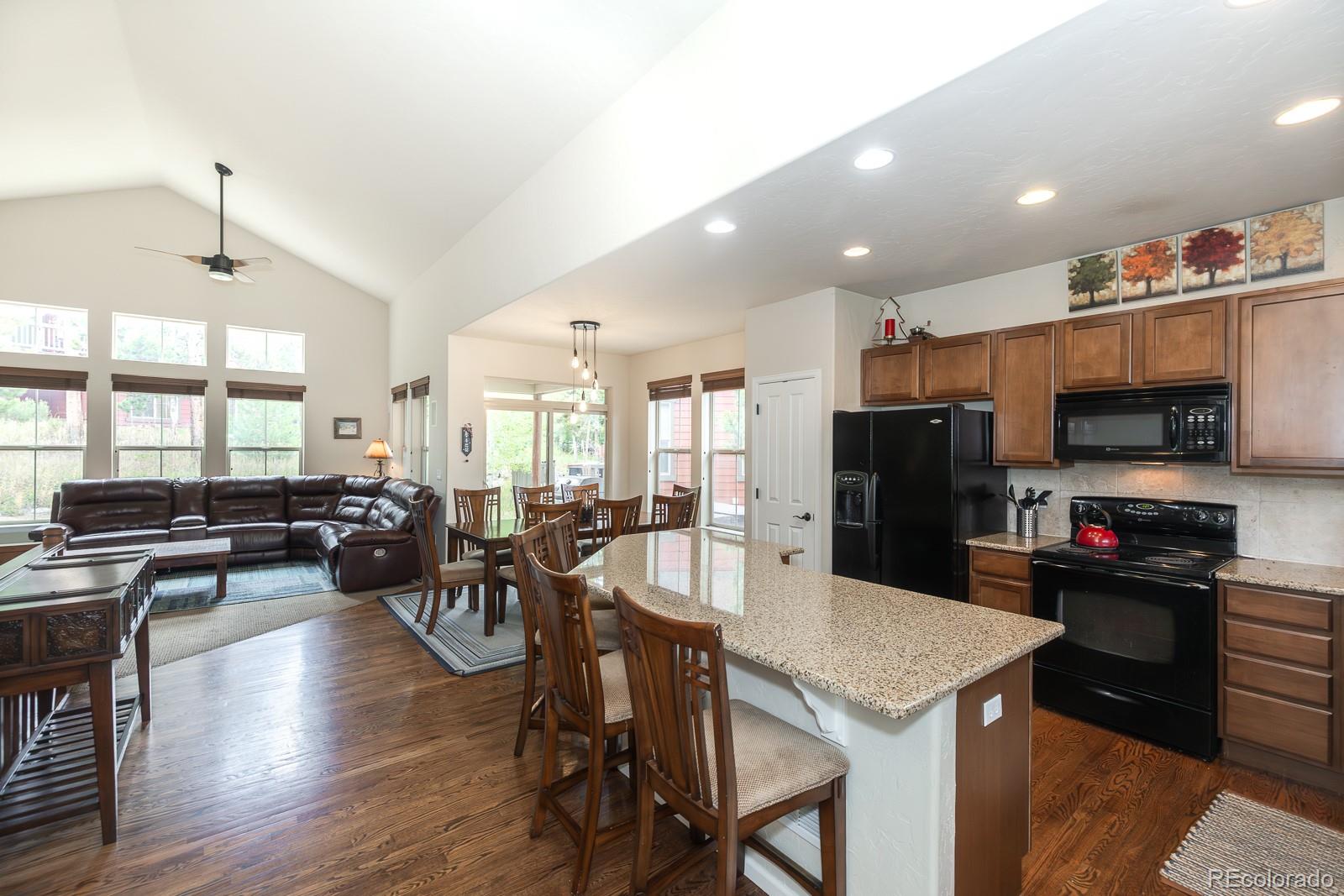 103 Timber Court Granby, CO 80446 - Photo 17 of 50 a kitchen with stainless steel appliances kitchen island granite countertop a refrigerator a stove a sink a dining table and chairs with wooden floor