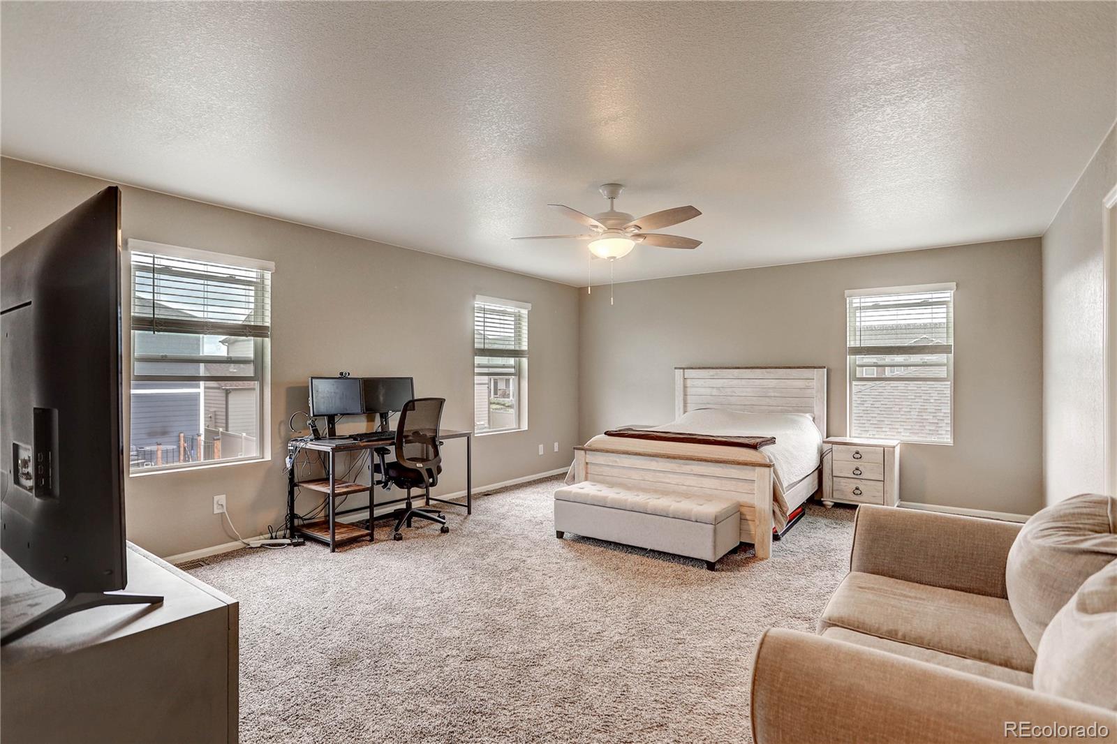 7104 Morrison Drive Frederick, CO 80530 - Photo 27 of 33 a spacious bedroom with a bed a couch and a chandelier