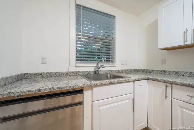 a kitchen with granite countertop cabinets sink and window