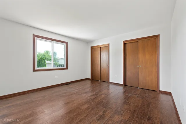 an empty room with wooden floor windows and closet