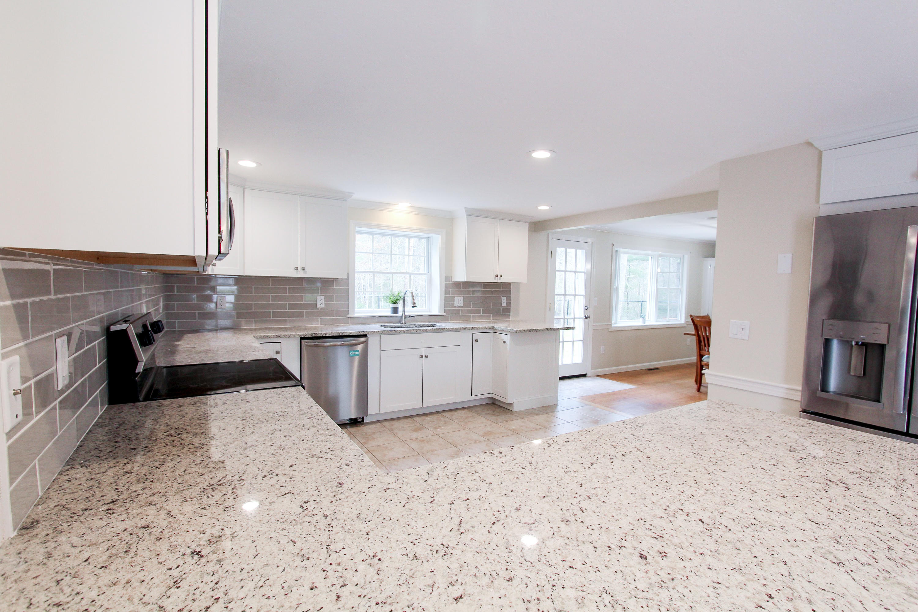 199 Skunknet Road Centerville, MA 02632 - Photo 10 of 37 a large kitchen with stainless steel appliances granite countertop a stove a sink a refrigerator and white cabinets with wooden floor