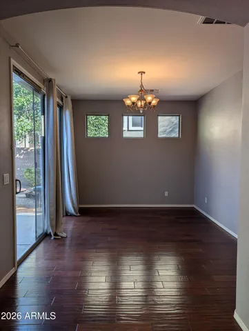 an empty room with wooden floor chandelier and windows