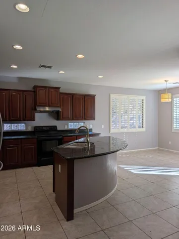 a kitchen with kitchen island granite countertop a sink and a stove