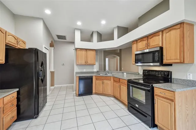 a kitchen with stainless steel appliances granite countertop a refrigerator and a stove top oven