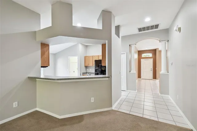 a view of a hallway to a room with wooden floor and cabinet
