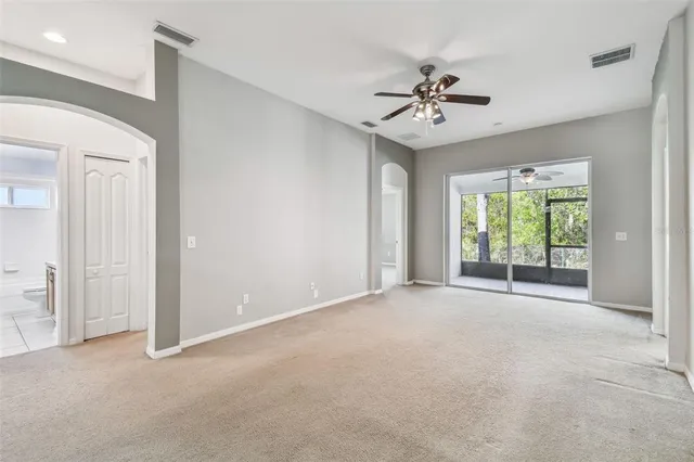 an empty room with windows and ceiling fan