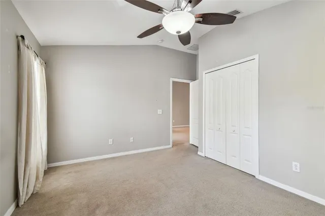 an empty room with closet and a chandelier fan