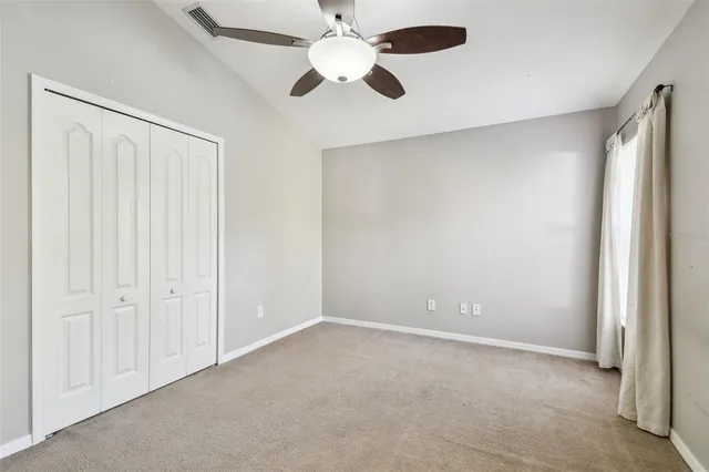 an empty room with closet and a ceiling fan