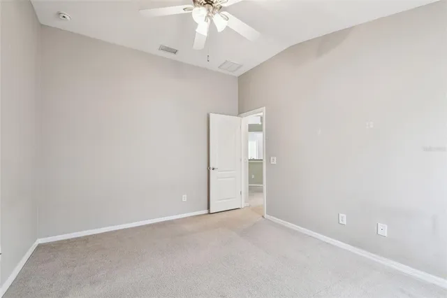 an empty room with a chandelier fan and closet