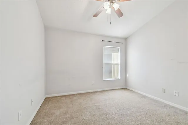 an empty room with a chandelier fan and windows