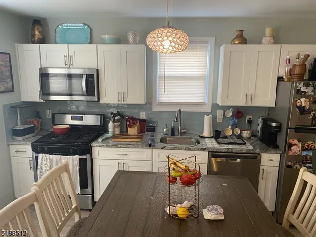 a kitchen with a stove a refrigerator and a dining table with wooden floor
