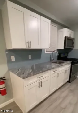 a kitchen with granite countertop white cabinets and a sink