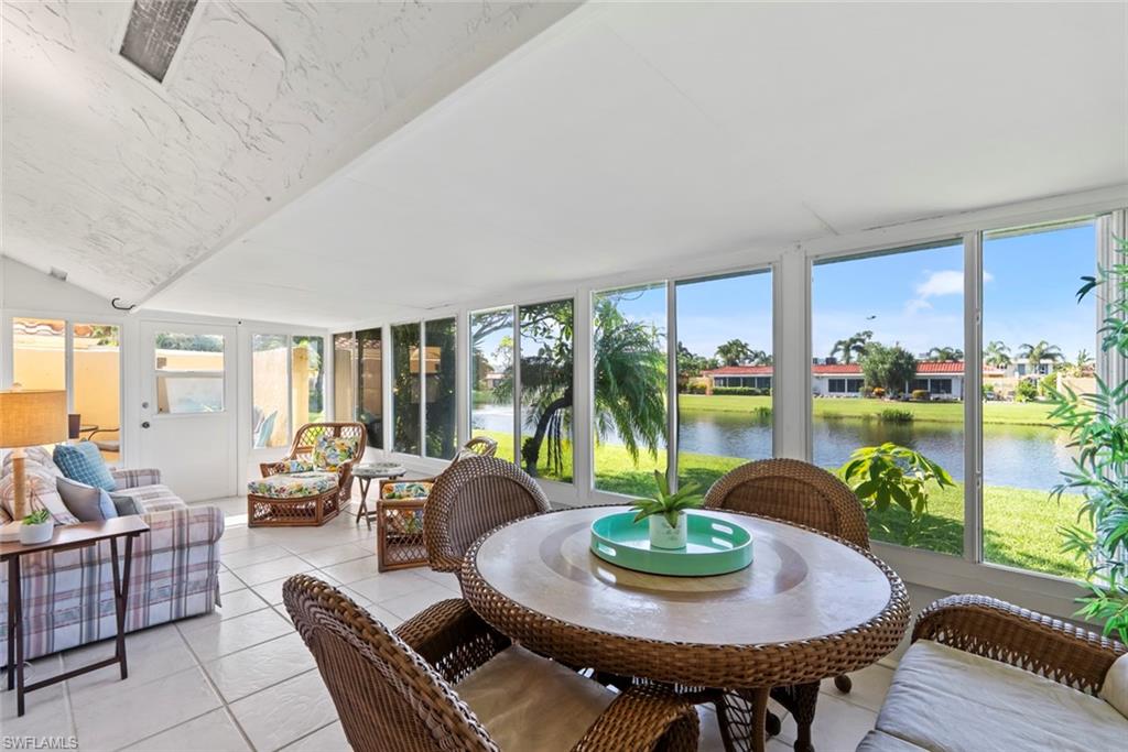 136 Harrison Road, Unit 1 Naples, FL 34112 - Photo 2 of 29 Expansive sunroom featuring floor-to-ceiling windows, ceramic tile flooring, and a panoramic water backdrop