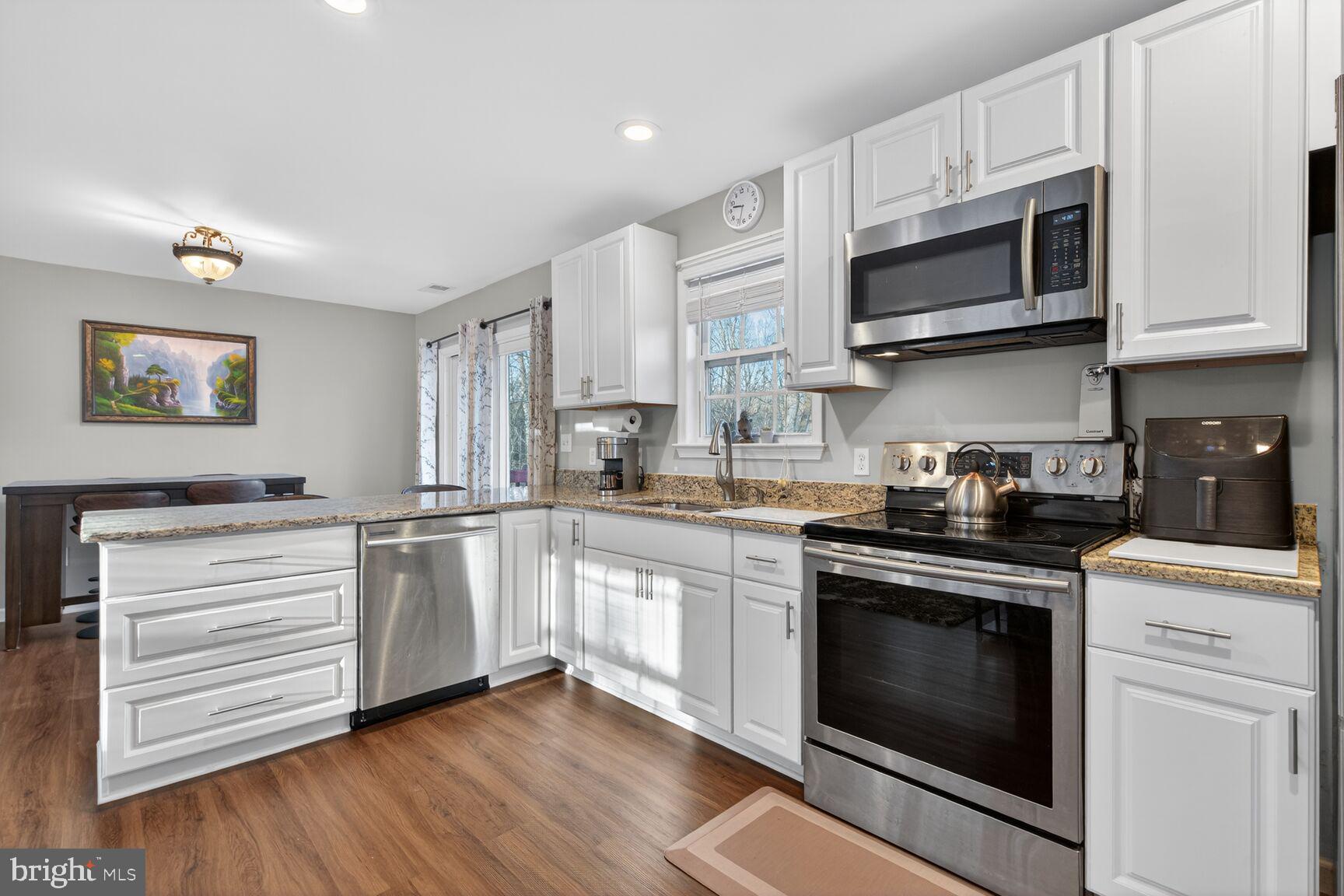 599 Widewater Road Stafford, VA 22554 - Photo 18 of 27 a kitchen with stainless steel appliances granite countertop white cabinets a sink a stove a microwave and wooden floors