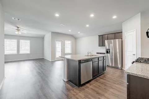 a large kitchen with stainless steel appliances granite countertop a large counter top a sink dishwasher and a refrigerator