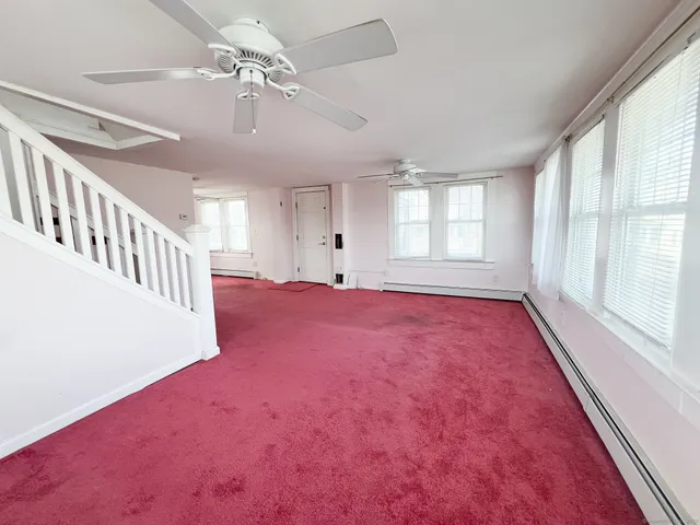 an empty room with windows and fan