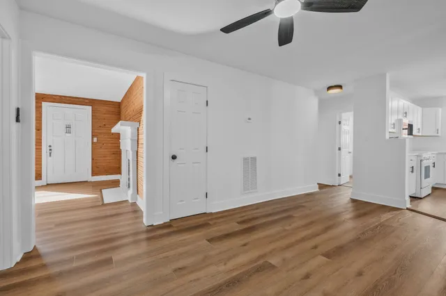 an empty room with wooden floor and a ceiling fan