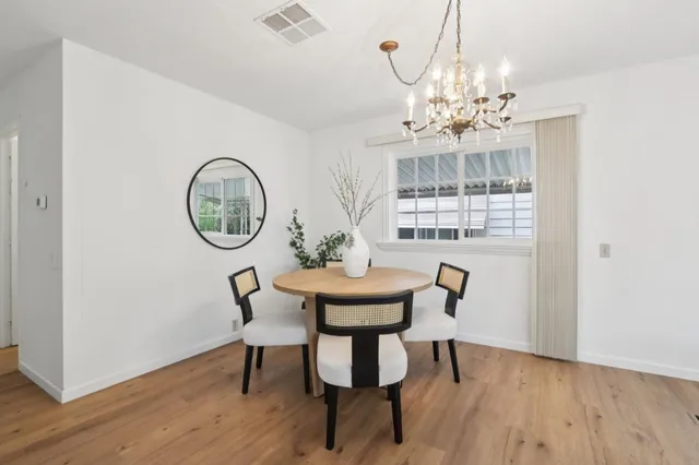 a view of a dining room with furniture a chandelier and wooden floor