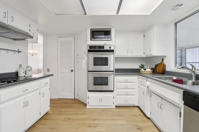 a kitchen with stainless steel appliances granite countertop a sink a stove and cabinets