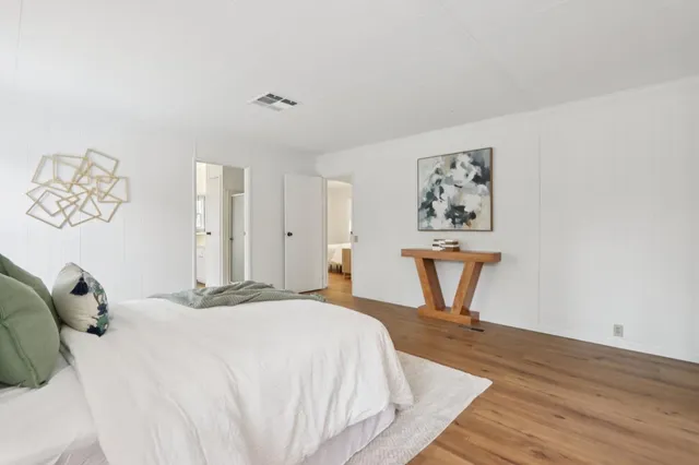 an empty room with wooden floor and a way to kitchen