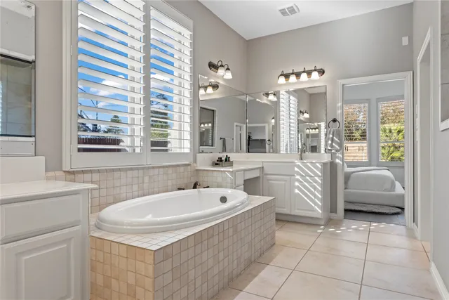 a spacious bathroom with a tub sink and mirror