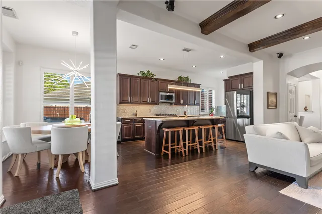 a living room with furniture and a dining table with wooden floor