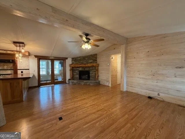 an empty room with wooden floor fireplace and windows